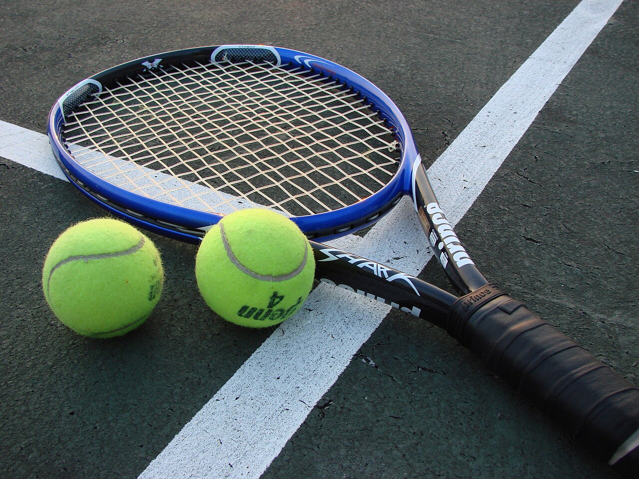 raquette de tennis et balles sur court pour progresser dans son sport